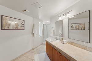 Full bath with tile patterned floors, vanity, a shower with curtain, and baseboards