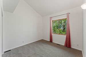 Carpeted empty room featuring lofted ceiling and baseboards