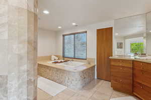 Bathroom featuring vanity, a bath, tile patterned floors, and recessed lighting