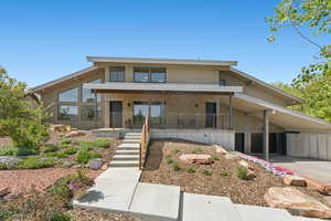 View of front of home featuring covered porch, stucco siding, an attached carport, and stairs