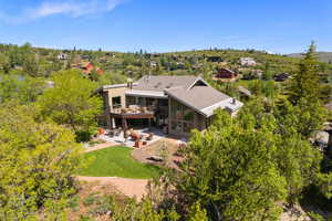Rear view of house with a patio, a sunroom, a balcony, and roof with shingles