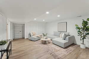 Living room with light wood-style floors, recessed lighting, and baseboards