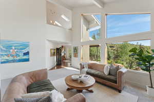 Living area featuring a high ceiling, baseboards, and beam ceiling
