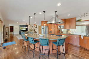 Kitchen with stainless steel appliances, light stone counters, light wood-style flooring, a spacious island, and recessed lighting
