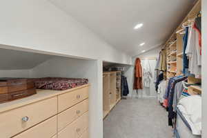 Spacious closet with vaulted ceiling and light colored carpet