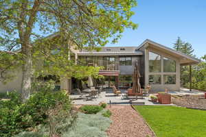 Rear view of property featuring a patio, a balcony, stucco siding, and a yard