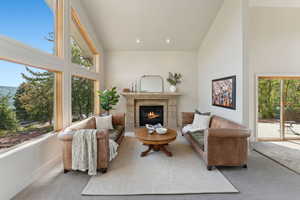 Living room with high vaulted ceiling, carpet, baseboards, a fireplace, and recessed lighting