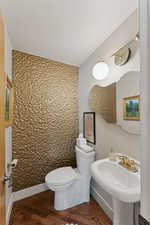Bathroom featuring toilet, wood finished floors, and a sink