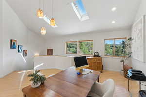 Office area with light wood finished floors, lofted ceiling, a skylight, baseboards, and recessed lighting