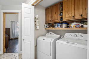 Laundry area featuring separate washer and dryer, light hardwood / wood-style floors, and cabinets