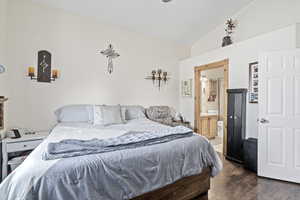 Bedroom featuring lofted ceiling, dark hardwood / wood-style floors, and ensuite bath