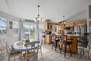 Dining area with a wealth of natural light, lofted ceiling, a chandelier, and light tile patterned floors