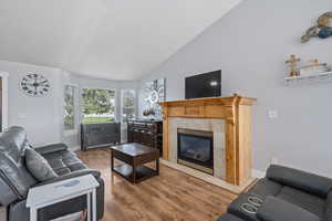 Living room featuring hardwood / wood-style floors, high vaulted ceiling, and a tile fireplace