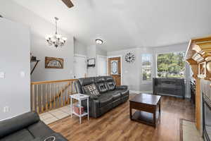 Living room with a notable chandelier, hardwood / wood-style flooring, and lofted ceiling