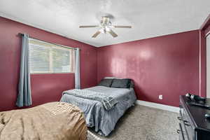 Carpeted bedroom with ceiling fan and a textured ceiling