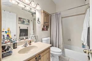 Full bathroom with vanity, toilet, shower / bathtub combination with curtain, and tile patterned flooring