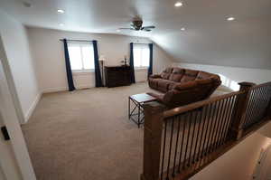 Living room with light carpet, ceiling fan, and vaulted ceiling