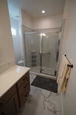 Bathroom with toilet, a shower with shower door, and vanity