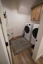 Laundry room featuring cabinets, dark hardwood / wood-style floors, and washing machine and clothes dryer