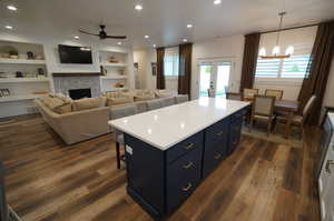 Kitchen with blue cabinetry, dark hardwood / wood-style floors, a center island, and pendant lighting