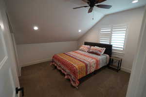 Carpeted bedroom with ceiling fan and lofted ceiling