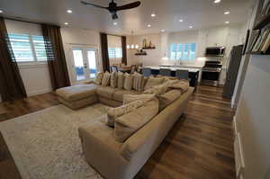 Living room featuring dark hardwood / wood-style floors, ceiling fan with notable chandelier, and a wealth of natural light