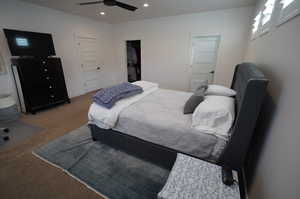 Carpeted bedroom featuring a walk in closet and ceiling fan