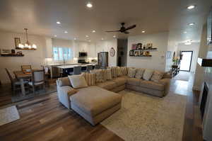 Living room featuring sink, dark wood-type flooring, and ceiling fan with notable chandelier