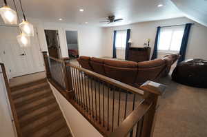 Living room featuring lofted ceiling, carpet flooring, and ceiling fan