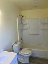 Full bathroom with vanity, shower / tub combination, wood-type flooring, and toilet