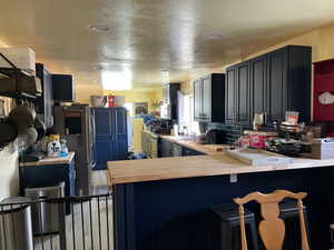 Main House Kitchen with sink, backsplash, wood counters, kitchen peninsula, and a kitchen breakfast bar