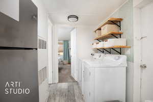 Clothes washing area featuring light hardwood / wood-style floors and washing machine and clothes dryer