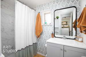 Bathroom featuring vanity, walk in shower, and washer / dryer