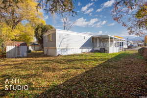 Rear view of property with a storage unit and a lawn