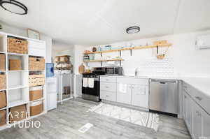 Kitchen featuring decorative backsplash, appliances with stainless steel finishes, washer and dryer, light hardwood / wood-style flooring, and sink