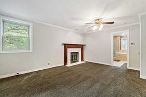 Unfurnished living room featuring a textured ceiling, carpet floors, a high end fireplace, ceiling fan, and crown molding