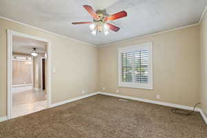 Empty room featuring a textured ceiling, carpet flooring, and ceiling fan