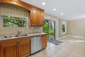 Kitchen with sink, light tile patterned floors, ornamental molding, and dishwasher