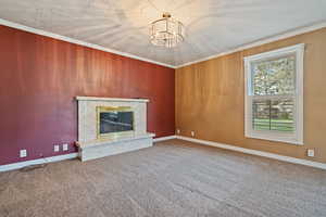 Unfurnished living room featuring a premium fireplace, ornamental molding, and a chandelier