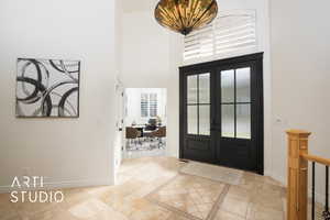 Tiled entrance foyer featuring french doors and a towering ceiling