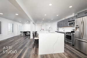 Kitchen with a waterfall kitchen island with sink, appliances with stainless steel finishes,