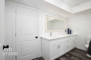 Bathroom with vanity and anti-fog mirrors, toilet, and hardwood / wood-style flooring