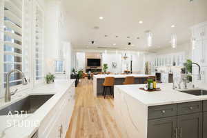 Kitchen featuring a spacious island, light stone counters, sink, and white cabinets