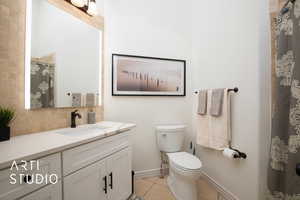 Bathroom with curtained shower, toilet, tile patterned floors, vanity, and decorative backsplash