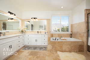 Bathroom featuring vanity with anti fog mirrors and a relaxing tiled tub