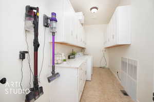 Pantry and laundry area with light tile patterned flooring, radiator, separate washer and dryer, and cabinets for pantry storage