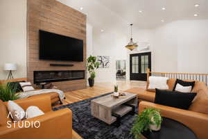 Living room with a large fireplace, french doors, wood-type flooring, and high vaulted ceiling