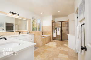 Bathroom featuring vanity with anti fog mirrors and shower with separate bathtub