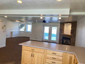 Kitchen with dark carpet, light brown Hickory cabinets, a textured ceiling, and ceiling fan