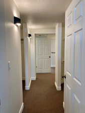 Corridor with dark carpet and a textured ceiling